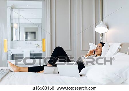 Stock Photo - Businesswoman using smartphone and laptop in suite. Fotosearch