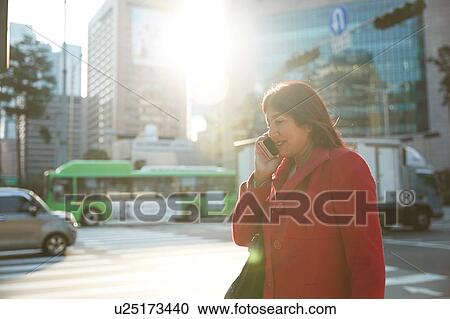 Stock Image - Businesswoman using smartphone in city, Seoul, South Korea. Fotosearch