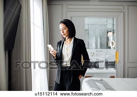 Businesswoman using smartphone in suite View Large Photo Image Picture - Businesswoman using smartphone in suite. Fotosearch