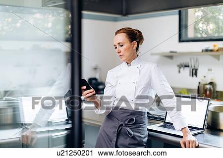 Chef using cellphone in kitchen View Large Photo Image Stock Image - Chef using cellphone in kitchen. Fotosearch