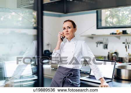Stock Photograph - Chef using cellphone in kitchen. Fotosearch