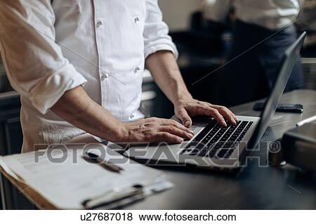 Stock Photo - Chef using laptop in kitchen. Fotosearch
