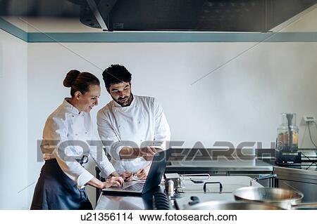 Chefs having discussion over laptop in kitchen View Large Photo Image Picture - Chefs having discussion over laptop in kitchen. Fotosearch