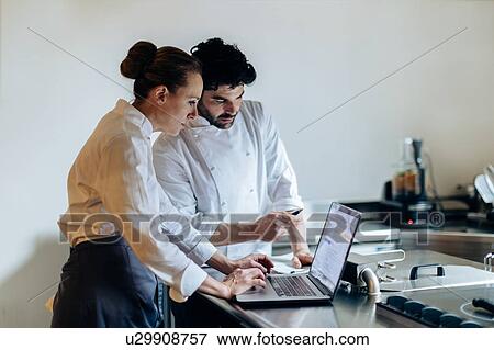 Stock Photo - Chefs having discussion over laptop in kitchen. Fotosearch