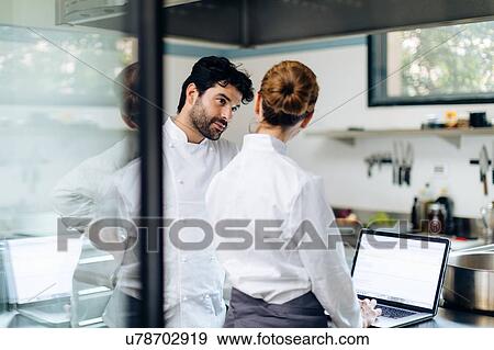 Chefs having discussion over laptop in kitchen View Large Photo Image Stock Photo - Chefs having discussion over laptop in kitchen. Fotosearch