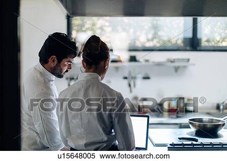 Chefs having discussion over laptop in kitchen View Large Photo Image Stock Photography - Chefs having discussion over laptop in kitchen. Fotosearch