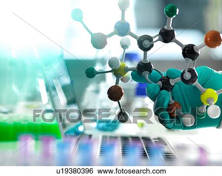 Stock Photograph - Chemistry research, researcher designing a chemical formula using a molecular model. Fotosearch