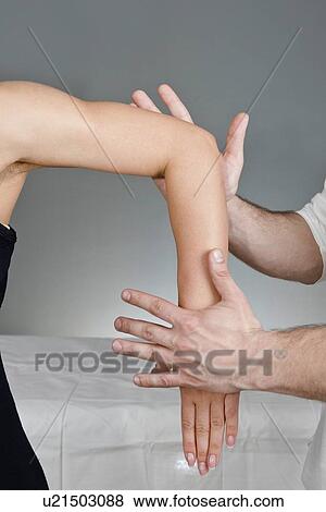 Stock Photo - Chiropractor examining patient's arm. Fotosearch