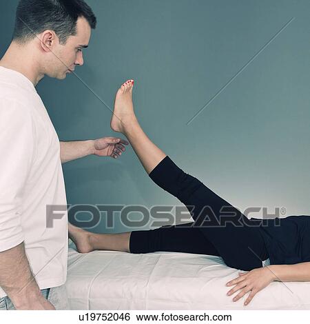 Chiropractor examining patient's leg View Large Photo Image Stock Photograph - Chiropractor examining patient's leg. Fotosearch