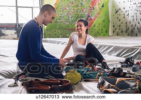 Stock Image - Climber friends on crash pad working with and learning about climbing equipment. Fotosearch