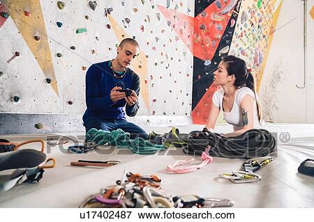 Stock Photo - Climber friends on crash pad working with and learning about climbing equipment. Fotosearch