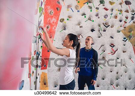 Stock Image - Climber friends talking at foot of climbing wall. Fotosearch