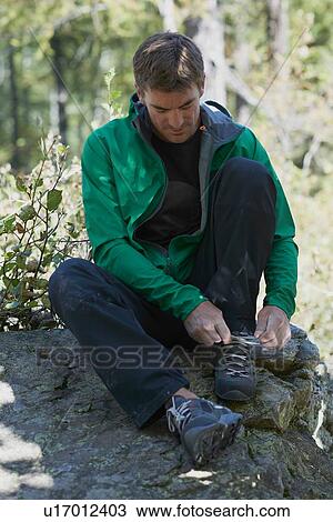 Stock Image - Climber tying shoelace, Chamonix, Rhone-Alps, France. Fotosearch