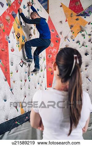 Stock Photo - Climber watching friend on climbing wall. Fotosearch