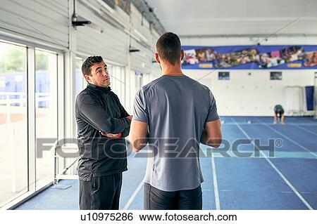 Coach and runner speaking in indoor running track View Large Photo Image Stock Photograph - Coach and runner speaking in indoor running track. Fotosearch