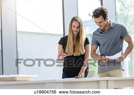 Stock Photograph - Colleagues brainstorming by glass wall. Fotosearch