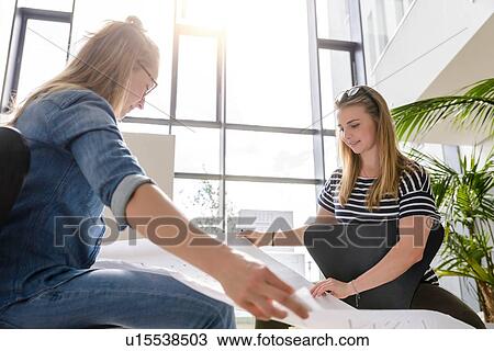 Stock Image - Colleagues brainstorming over charts in bright sunlight. Fotosearch