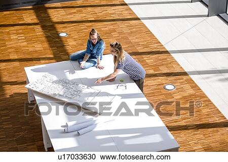 Colleagues brainstorming over plans View Large Photo Image Stock Image - Colleagues brainstorming over plans. Fotosearch