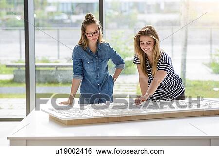Stock Photograph - Colleagues brainstorming over architectural model. Fotosearch