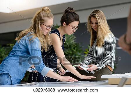 Stock Photo - Colleagues brainstorming with colour charts. Fotosearch