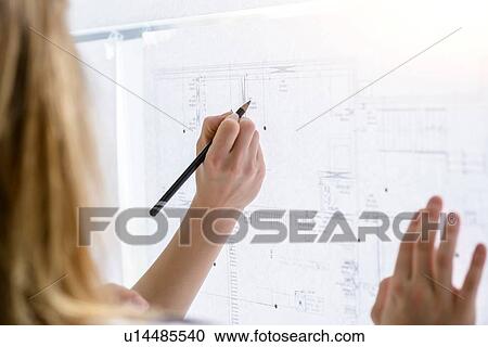 Stock Image - Colleagues discussing plans on glass wall. Fotosearch