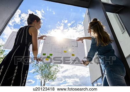 Colleagues discussing plans on glass wall View Large Photo Image Stock Photo - Colleagues discussing plans on glass wall. Fotosearch