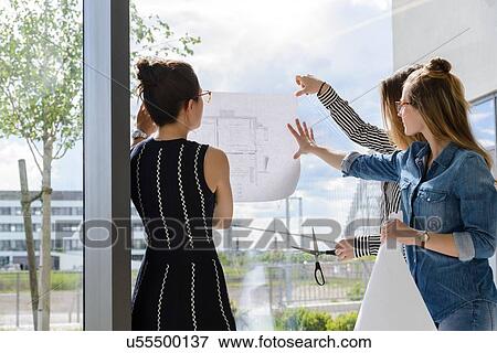 Colleagues discussing plans on glass wall View Large Photo Image Stock Photo - Colleagues discussing plans on glass wall. Fotosearch