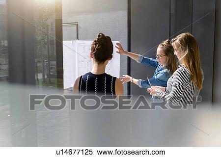 Colleagues discussing plans on glass wall View Large Photo Image Stock Photography - Colleagues discussing plans on glass wall. Fotosearch