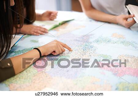 Stock Photograph - College students studying world map in classroom. Fotosearch