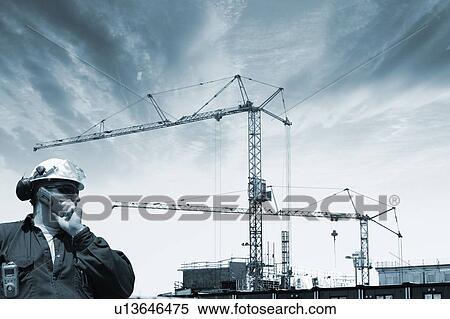 Construction worker talking on mobile phone, with cranes and scaffolding in the background. View Large Photo Image Stock Photography - Construction worker talking on mobile phone, with cranes and scaffolding in the background.. Fotosearch