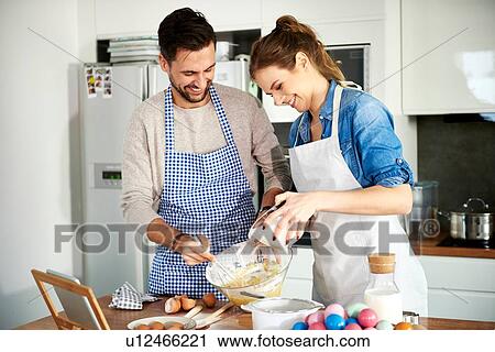 Stock Image - Couple baking in kitchen. Fotosearch