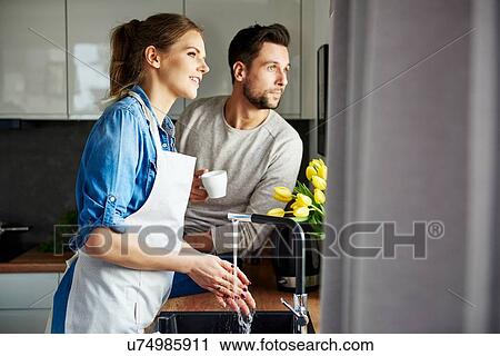 Couple drinking coffee and washing up in kitchen View Large Photo Image Stock Image - Couple drinking coffee and washing up in kitchen. Fotosearch