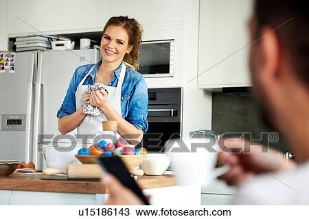Stock Image - Couple talking and baking in kitchen. Fotosearch