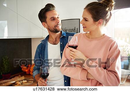 Stock Photo - Couple talking and drinking red wine in kitchen. Fotosearch
