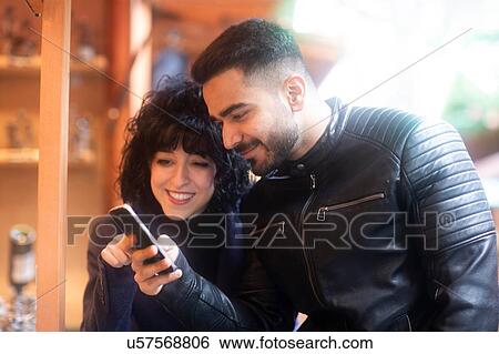 Couple using smartphone at Christmas market, Freiburg, Baden-Wurttemberg, Germany View Large Photo Image Stock Photograph - Couple using smartphone at Christmas market, Freiburg, Baden-Wurttemberg, Germany. Fotosearch