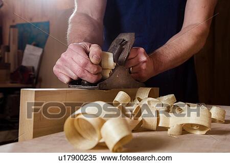 Stock Photography - Craftsman using wood plane in workshop. Fotosearch