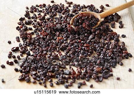Stock Photo - Currants and raisins on table with wooden spoon, overhead view. Fotosearch