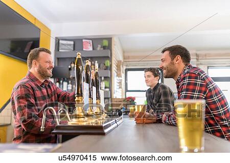 Stock Photography - Customers and server drinking beer in small brewery. Fotosearch