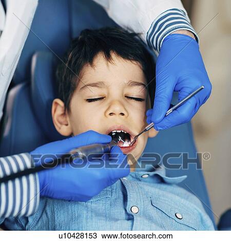 Dentist drilling young boy's tooth View Large Photo Image Stock Image - Dentist drilling young boy's tooth. Fotosearch