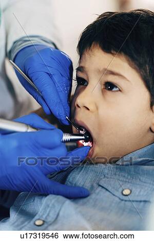 Stock Photograph - Dentist drilling young boy's tooth. Fotosearch