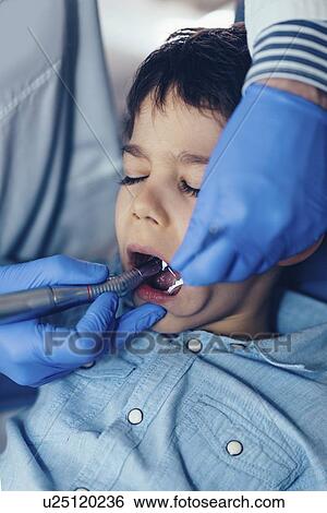Stock Photograph - Dentist drilling young boy's tooth. Fotosearch