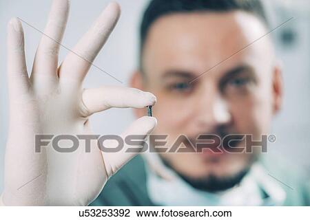 Dentist holding dental implant View Large Photo Image Stock Image - Dentist holding dental implant. Fotosearch