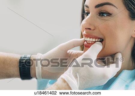 Stock Image - Dentist inspecting woman's teeth. Fotosearch