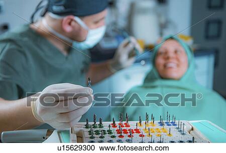 Stock Image - Dentist installing dental implant. Fotosearch