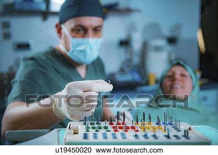 Stock Image - Dentist installing dental implant. Fotosearch