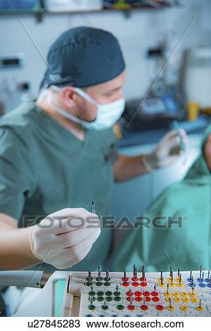 Stock Image - Dentist installing dental implant. Fotosearch