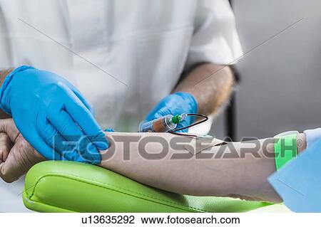 Stock Image - Drawing blood for platelet-rich plasma (PRP) treatment. Doctor drawing blood for a PRP cosmetics treatment.. Fotosearch