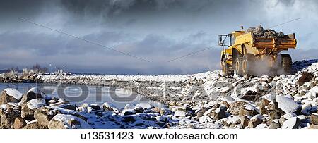 Dumper truck moving large rocks from the sea-bed in winter. View Large Photo Image Stock Image - Dumper truck moving large rocks from the sea-bed in winter.. Fotosearch