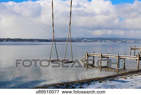 Stock Photo - Empty swing near pier, Lake Starnberg, Bavaria, Germany. Fotosearch