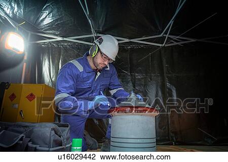 Stock Image - Engineer crack testing large part in turbine hall of nuclear power station. Fotosearch